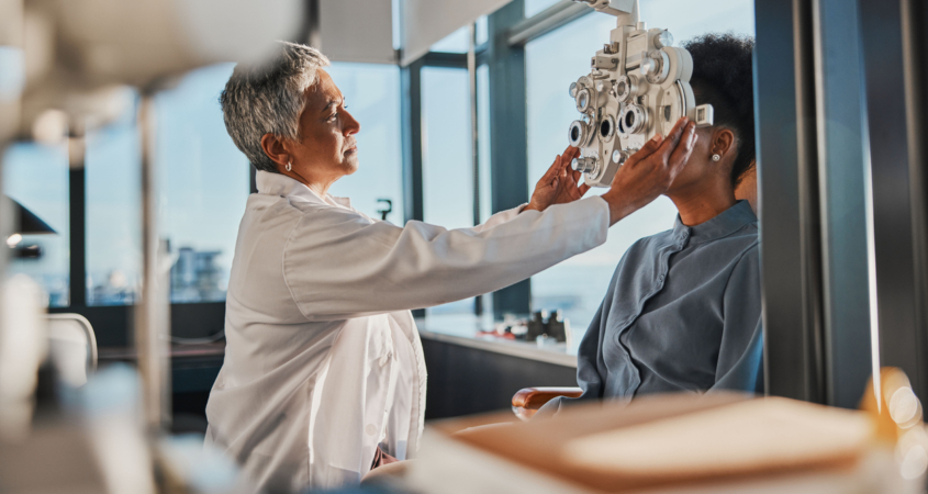 Elderly optometrist woman, eye exam patient and medical goal in hospital, consulting room and office with help. Senior optician, eyesight test and phoropter for wellness, health and vision analysis