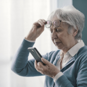 Senior woman having vision problems, she can't read the messages on her smartphone