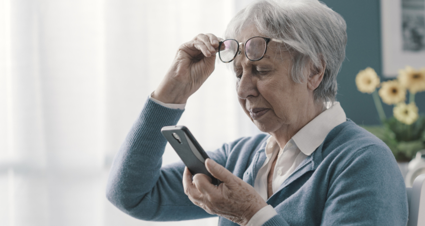 Senior woman having vision problems, she can't read the messages on her smartphone